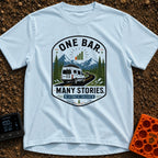 One Bar Many Stories - T-Shirt in Chambray - A badge-style design showing a white camper van driving along a winding...
