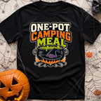 One Pot Wonder - T-Shirt in Black - The text "ONE-POT CAMPING MEAL" is displayed above an illustration of a black witch's...
