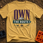 Own The Route - T-Shirt in Mustard - The design features the large text "OWN" behind a white camper van, with the words...