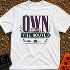 Own The Route - T-Shirt in White - The design features the large text "OWN" behind a white camper van, with the words...