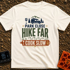 Hike Far Cook Slow - T-Shirt in Ivory - A typographic graphic showing a camper van parked near mountains and pine trees,...