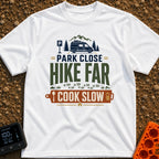 Hike Far Cook Slow - T-Shirt in White - A typographic graphic showing a camper van parked near mountains and pine trees,...