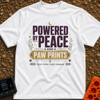 Peaceful Paw Power - T-Shirt in White - A typographic design featuring the phrases "POWERED BY PEACE AND PAW PRINTS" and...