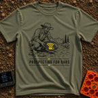 Panning For Signal - T-Shirt in Moss - A black and white illustration of a gold prospector squatting by a stream, holding...