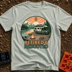 Retired and Rebooted - T-Shirt in Bay - A circular illustration of a green and white RV parked beside a mountain lake...