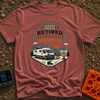 Retired But Recharged - T-Shirt in Brick - A graphic badge depicting a white campervan parked in a mountainous landscape...