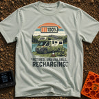 Retired And Recharging - T-Shirt in Bay - A green Class C camper van with rooftop solar panels is parked by a lake and...