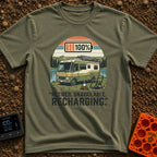 Recharging In Progress - T-Shirt in Moss - An illustration of a green and white motorhome parked by a lake with mountains...