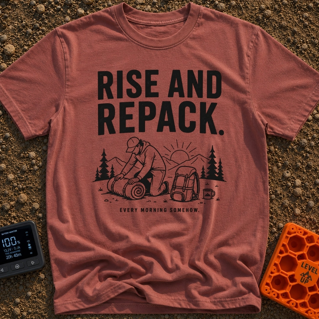 Rise And Repack - T-Shirt in Brick - A black-and-white illustration of a man kneeling to roll up a sleeping bag, with a...