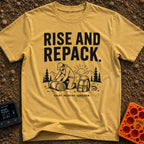 Rise And Repack - T-Shirt in Mustard - A black-and-white illustration of a man kneeling to roll up a sleeping bag, with a...