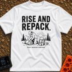 Rise And Repack - T-Shirt in White - A black-and-white illustration of a man kneeling to roll up a sleeping bag, with a...
