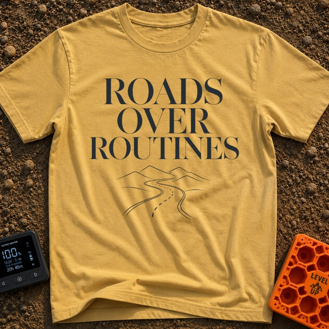 Bypass The Routine - T-Shirt in Mustard - The design features the stacked text "ROADS OVER ROUTINES" in a large, serif...