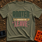 Rooted Yet Roaming - T-Shirt in Moss - A typographic design reading "ROOTED ENOUGH TO LEAVE" with roots drawn inside the...