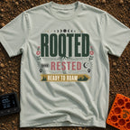Rooted Ready To Roam - T-Shirt in Bay - A typographic design featuring the word "ROOTED" with tree roots growing from the...
