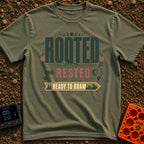 Rooted Ready To Roam - T-Shirt in Moss - A typographic design featuring the word "ROOTED" with tree roots growing from...