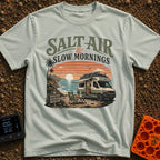 Sunrise Sips & Sea - T-Shirt in Bay - A camper van is parked on a coastal cliff overlooking the ocean at sunrise, with a...