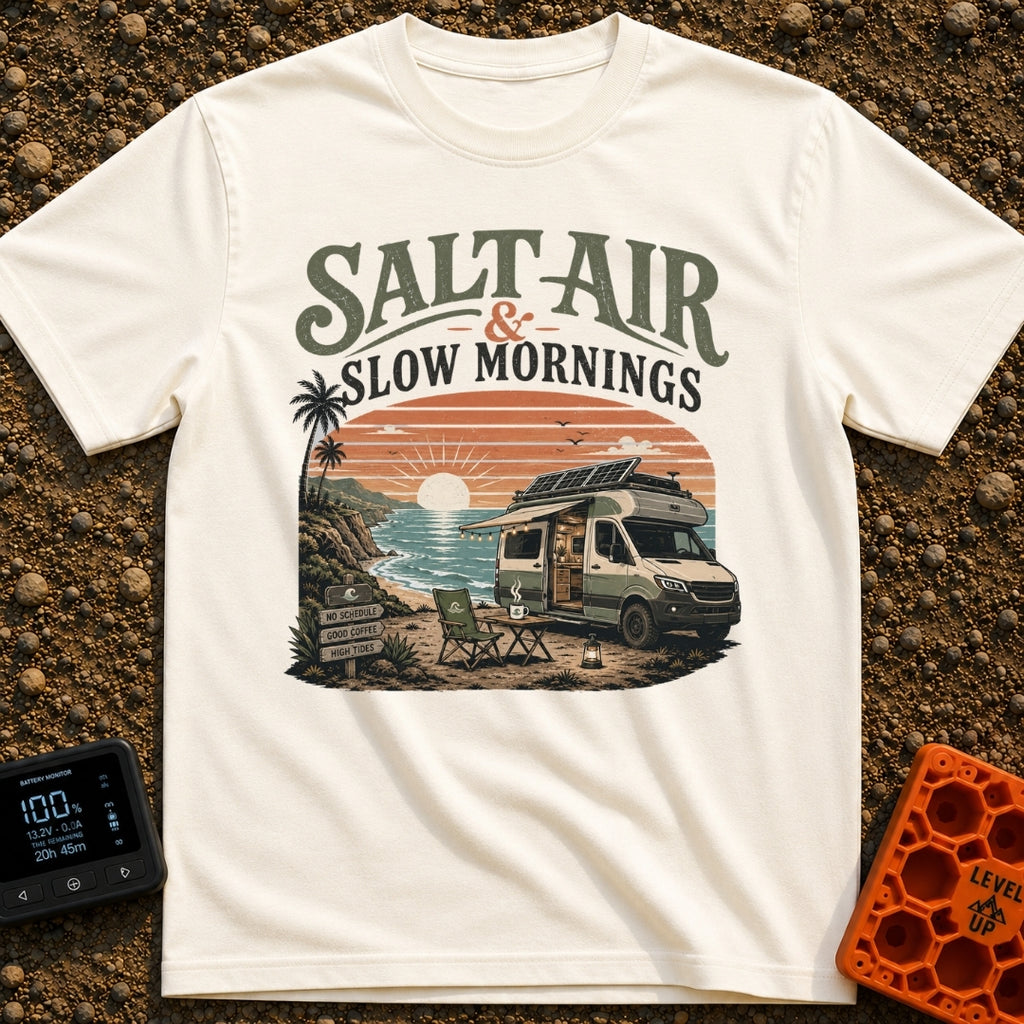Sunrise Sips & Sea - T-Shirt in Ivory - A camper van is parked on a coastal cliff overlooking the ocean at sunrise, with...