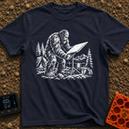 Sasquatch Seeking Signal - T-Shirt in Navy - A black-and-white illustration of a Sasquatch adjusting a flat satellite...