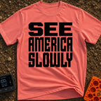 Go Slow, America - T-Shirt in Watermelon - Bold, black, block text stacked in three lines reading 'SEE AMERICA SLOWLY' on...
