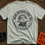 Solar Watchers Union - T-Shirt in Bay - A black-and-white circular badge design featuring a stylized sun with a face...
