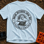 Solar Watchers Union - T-Shirt in Chambray - A black-and-white circular badge design featuring a stylized sun with a face...