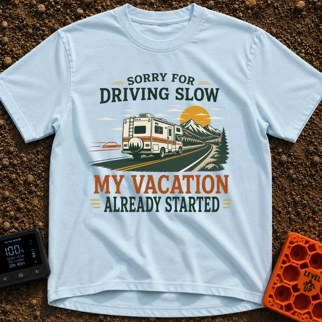 Pardon My Pace - T-Shirt in Chambray - A white Class C motorhome drives along a two-lane highway toward mountains and a...