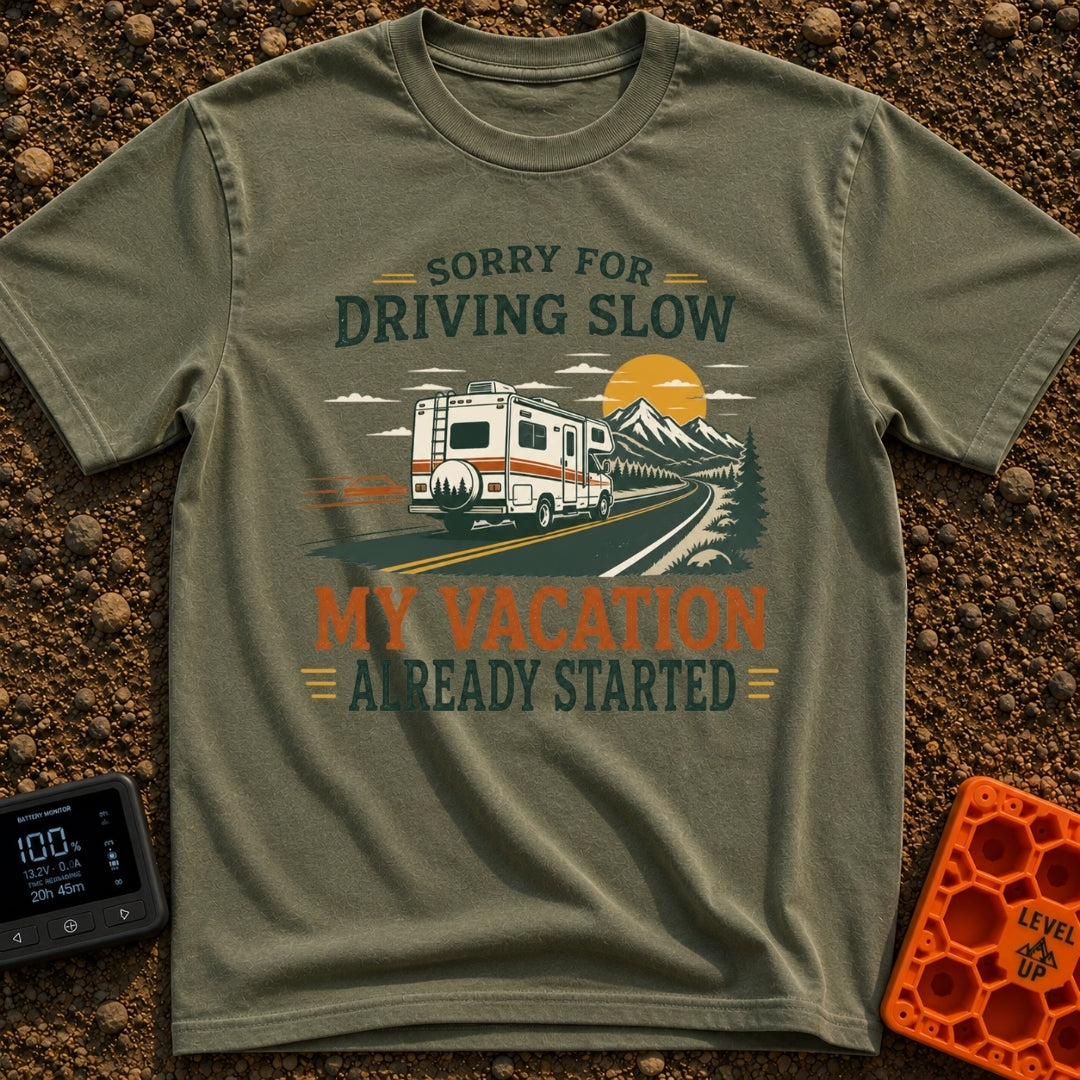 Pardon My Pace - T-Shirt in Moss - A white Class C motorhome drives along a two-lane highway toward mountains and a...