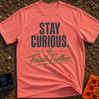 Curiosity Travels Further - T-Shirt in Watermelon - A typographic design featuring the words "STAY CURIOUS." in large,...
