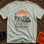 Stretch And Recharge - T-Shirt in Bay - A silhouette of a woman doing a yoga pose on a mat beside an RV camper parked...