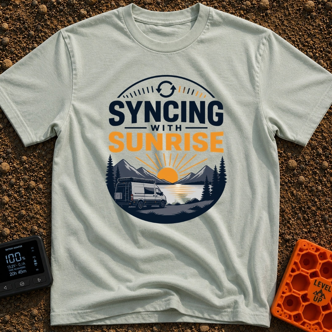 Rise And Sync - T-Shirt in Bay - A circular badge design featuring a white camper van parked by a lake with mountains and...