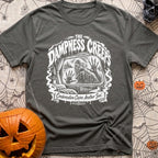 The Damp Creeps In - T-Shirt in Pepper - A black-and-white illustration of a swamp creature with webbed hands pressing...