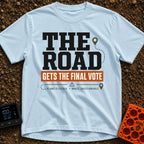 The Road Votes Last - T-Shirt in Chambray - A typographic design featuring the large text "THE ROAD" above a brown banner...