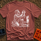 In Bubble We Trust - T-Shirt in Brick - A white line-art illustration showing a bearded man kneeling beside a camper...