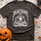 The Solar Seance - T-Shirt in Graphite - A vintage-style white line drawing of a hooded figure holding up foldable solar...