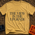 Upgrade To The View - T-Shirt in Mustard - A minimalist, text-focused design featuring the stacked phrase "THE VIEW IS...