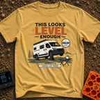 Leaning Tower Camper - T-Shirt in Mustard - A cartoon illustration of a white camper van parked on uneven terrain with...
