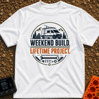 Lifetime Weekend Build - T-Shirt in White - A circular graphic showing a white camper van parked near pine trees and...